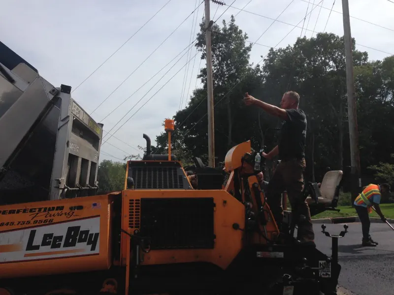 Paver and roller at work on a driveway