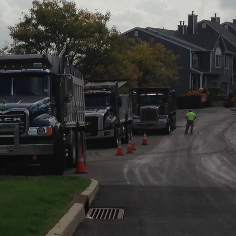 Dump trucks and crew paving a residential street